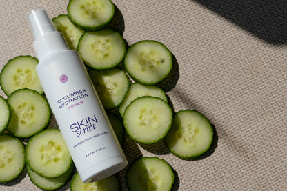 Skincare toner bottle labeled 'Skin Script' with sliced cucumbers on a textured surface